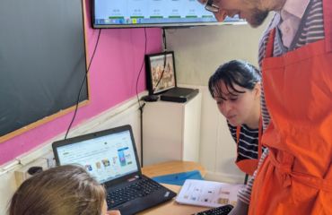 Two women and one man at a desk during the Living Skills course looking at the cost of ingredients