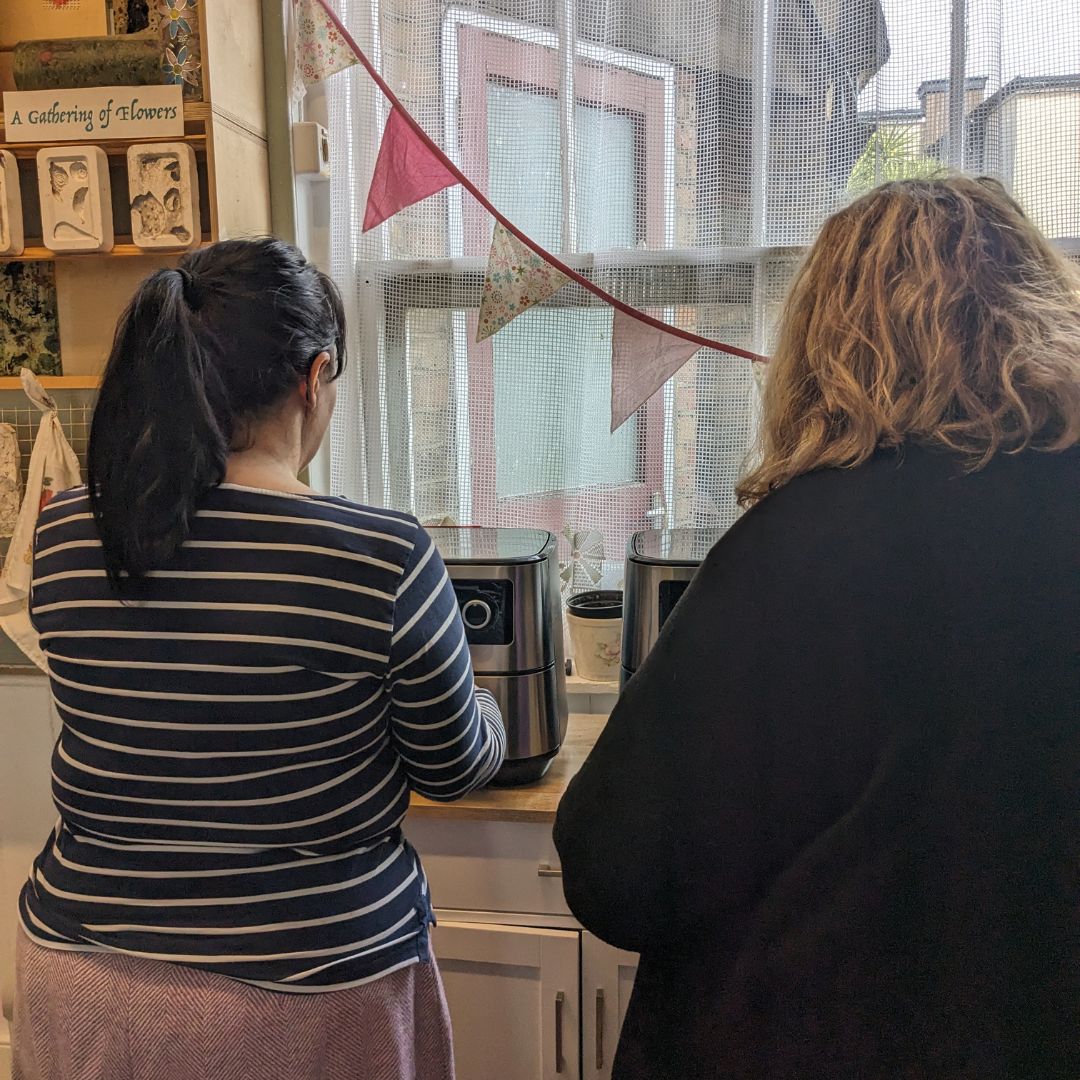 The backs of two ladies using the air fryers