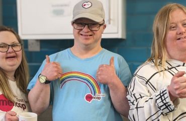 Lucy, Neil and Natalie smiling. Neil has his thumbs up and Lucy and Natalie are holding mugs