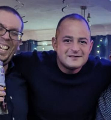 Three men smiling and holding drinks