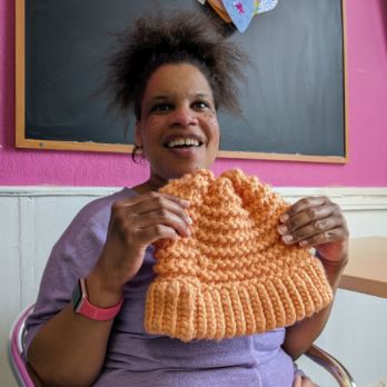 Rosie smiling and holding an orange hat