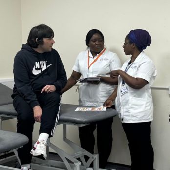 Two student nurses and man from Swale Hub sitting on a hospital bed