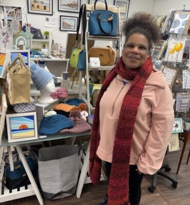Rosie, a member with a learning disability, standing in front of her handmade hats in an Art Gallery in Westgate.