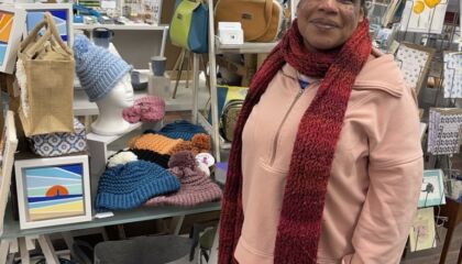 Rosie, a member with a learning disability, standing in front of her handmade hats in an Art Gallery in Westgate.