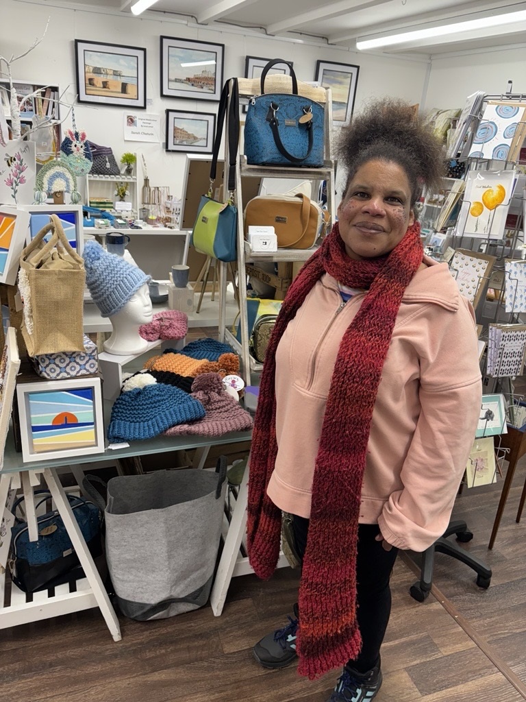 Rosie, a member with a learning disability, standing in front of her handmade hats in an Art Gallery in Westgate.