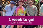 Three men sit together on a bench in the sunshine, smiling. They wear casual hats and sunglasses, and sit in front of a garden trellis. A purple banner over the photo reads: “1 week to go! Ashford Hub Open Day.”