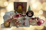 A collection of Christmas presents crafted by East Kent Herne Bay hub members, including pinecone reindeers, festive greeting cards and more. Twinkling white lights sit in the background.