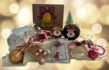 A collection of Christmas presents crafted by East Kent Herne Bay hub members, including pinecone reindeers, festive greeting cards and more. Twinkling white lights sit in the background.