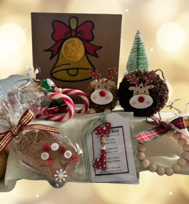 A collection of Christmas presents crafted by East Kent Herne Bay hub members, including pinecone reindeers, festive greeting cards and more. Twinkling white lights sit in the background.